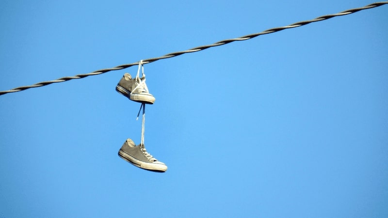 Hanging shoes on power lines is to…